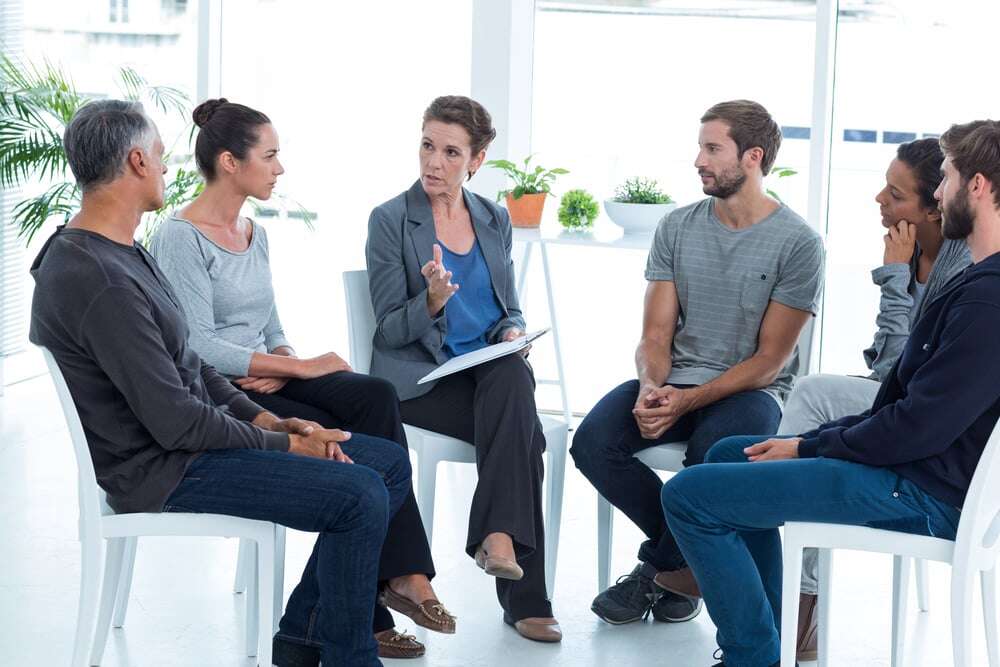 Group therapy in session sitting in a circle in a bright room-2